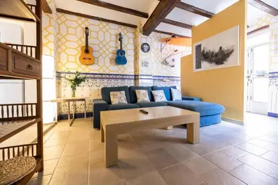 a living room with a blue couch and guitars on the wall at Boutique House Alzira in Alzira