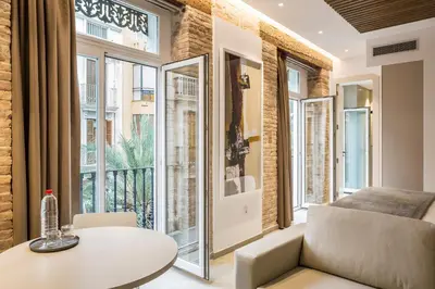 a living room with a table and a couch and large windows at Mon Suites Benlliure in Valencia