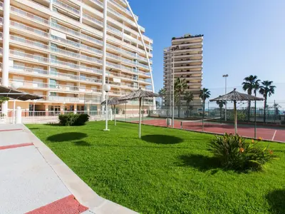 a lawn with umbrellas in front of a large building at Apartment Ana by Interhome in Cullera