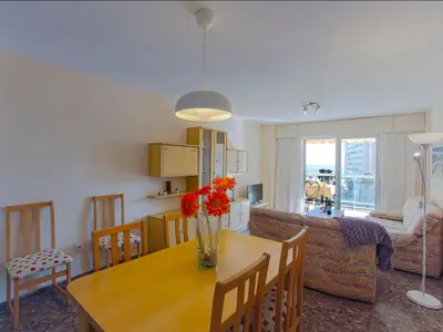 a kitchen and living room with a wooden table with flowers on it at Apartment Ana by Interhome in Cullera