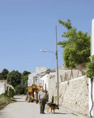 a man walking a dog down a street with a tractor at Villa Serrano, La casa rural de los mil suelos in Valencia