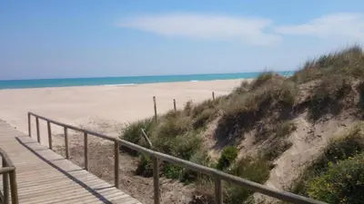 a wooden boardwalk leading to a beach with the ocean at UIM Mediterraneo Churruca Wifi in Puerto de Sagunto