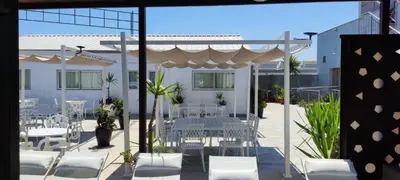 a patio with white chairs and tables and a white umbrella at Hotel Ruta Romana in Sagunto