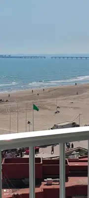 a view of a beach with a green flag and the ocean at 1ere soleil levant in Puerto de Sagunto