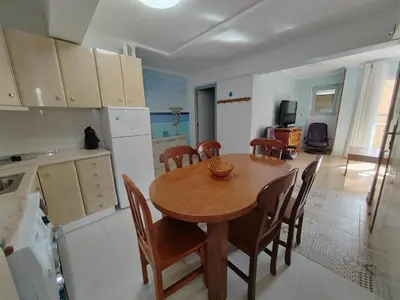 a kitchen and dining room with a wooden table and chairs at Tout près de la plage in Puerto de Sagunto