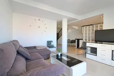 a living room with a couch and a clock on the wall at Global Vacacional, Impresionante ático para 8 personas en Canet d'en Berenguer in Canet de Berenguer