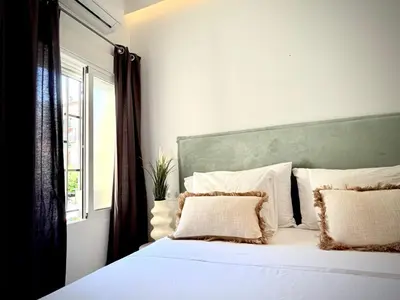 a white bed with a green headboard and a window at Apartamento Playa Valencia Beach in Valencia