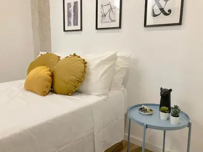 a white bed with yellow pillows and a side table at Valencia Playa in Valencia