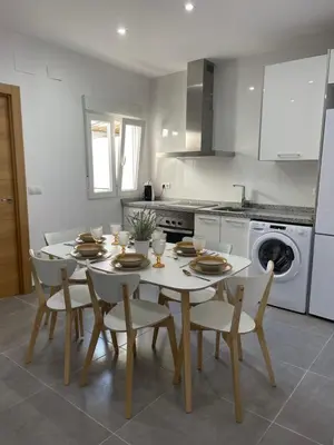 a kitchen with a white table and chairs and a kitchen with a stove at UIM Mediterraneo Segorbe 1 Wifi in Puerto de Sagunto