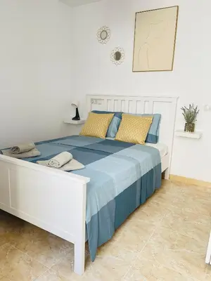 a white bed with blue and yellow pillows on it at UIM Mediterraneo Poeta 3 Wifi in Puerto de Sagunto