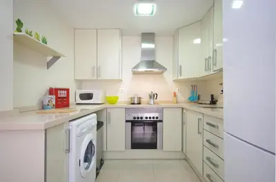 a kitchen with white cabinets and a washer and dryer at Apartamentos Port in Valencia