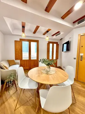a living room with a wooden table and white chairs at Casa del Carmen in Valencia