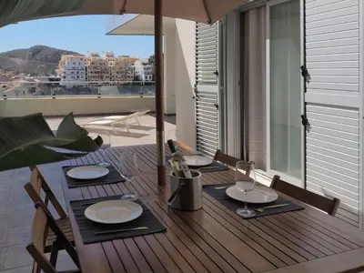 a wooden table with plates and wine glasses on a balcony at Villa with magnificants sea views on Cullera bay. in Faro de Cullera