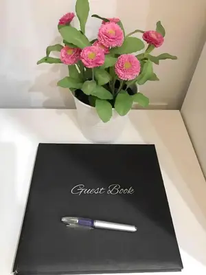 a black notebook with a pen and a vase of pink flowers at Estudio en el Corazón de Valencia al lado Catedral in Valencia