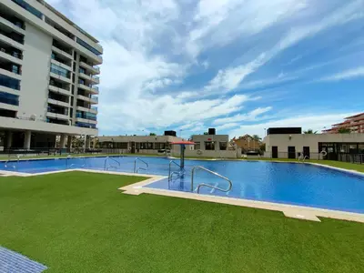 a large swimming pool with green grass next to a building at NON STRESS First Level in Valencia