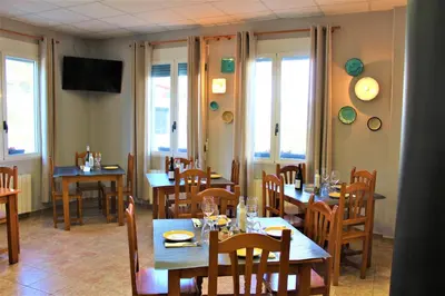 a restaurant with wooden tables and chairs and windows at Hostal Rural Fidel Garcia Guzman in Chera