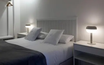 a bedroom with a bed with white pillows and a lamp at Dau Studios in Valencia