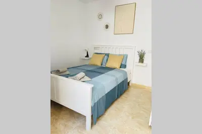 a bedroom with a white bed with blue and yellow pillows at UIM Mediterraneo Poeta 5 Wifi in Puerto de Sagunto