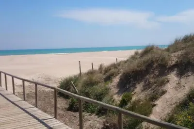 a sandy beach with a wooden boardwalk and the ocean at UIM Mediterraneo Poeta 6 Wifi in Puerto de Sagunto