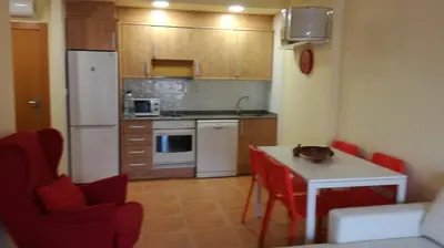 a kitchen with a white refrigerator and a table with red chairs at Nova Almenara. Ideal para familias in Barrio-Mar