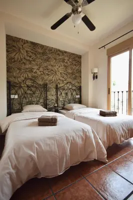 two beds in a bedroom with a ceiling fan at Casa El Cielo, in the heart of Old Town in Chulilla