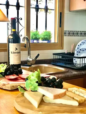 a kitchen counter with cheese and grapes and a bottle of wine at Casa El Cielo, in the heart of Old Town in Chulilla