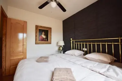 a bedroom with a large white bed with a ceiling fan at Casa El Cielo, in the heart of Old Town in Chulilla