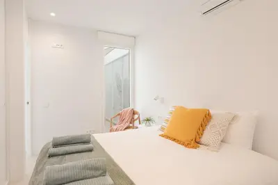 a white bedroom with a bed and a chair at Marsalada - Ground floor front line beach apartment in Playa de Mar