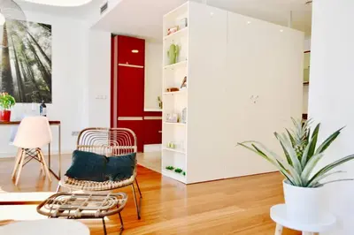 a living room with a rattan chair and a red door at Hola Valencia - Holiday Apartments in Valencia