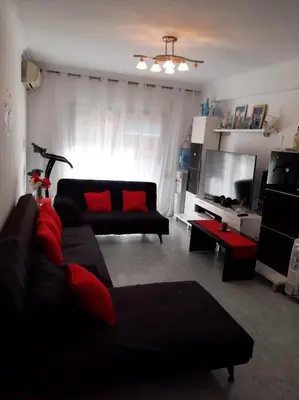 a living room with a black couch and red pillows at habitación pequeña en piso compartido con 2 adultos in Valencia