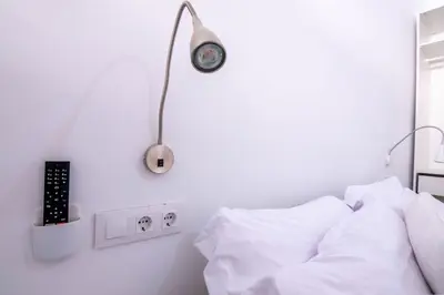 a white bedroom with a bed and a lamp at Arenas beach in Valencia