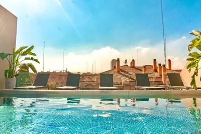 a swimming pool with chairs and a building in the background at Valencia Luxury - Sea Port II in Valencia