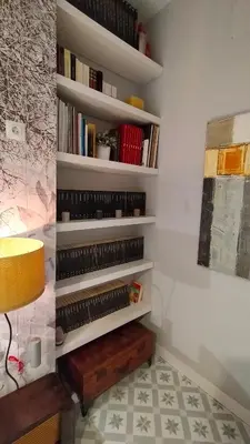 a book shelf with books and a lamp in a room at Blaucel Cafè i Habitacions in Cullera