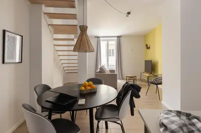 a living room with a table and chairs and a staircase at Líbere Valencia Jardín Botánico in Valencia