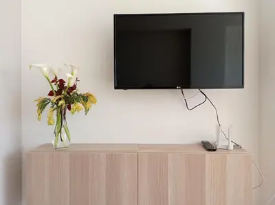 a tv on top of a cabinet with a vase of flowers at Apartamento en El Prado in Cullera