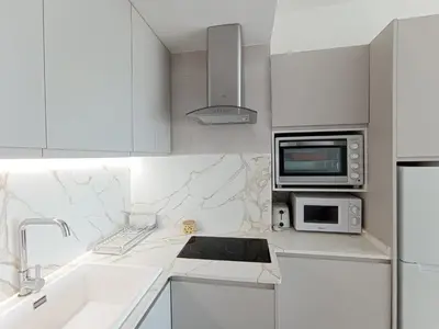 a white kitchen with a sink and a microwave at Apartamento en El Prado in Cullera