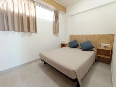 a bedroom with a bed with blue pillows and a window at Apartamento en El Prado in Cullera