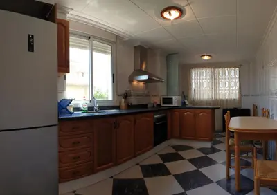 a kitchen with a refrigerator and a table at Vacansis Adosado Marenyet in Cullera