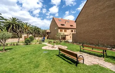 a park with benches and a building and palm trees at Palau de Vic in Valencia