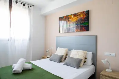 a bedroom with a white bed with a painting on the wall at FLORIT FLATS - The Malvarrosa Beach Apartment & Free Parking in Valencia