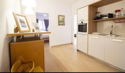 a kitchen with white cabinets and a wooden floor at Acogedor apartamento en Ruzafa-centro in Valencia