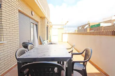 a table and chairs on the balcony of a building at Global Vacacional, Ático con 2 terrazas en la playa Puerto de Sagunto in Puerto de Sagunto