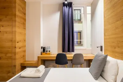 a bedroom with a bed and a desk with two chairs at NALU Valencia Boutique Rooms in Valencia