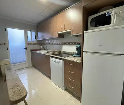 a kitchen with a white refrigerator and wooden cabinets at UIM Mediterraneo ATICO San Pedro Wifi in Puerto de Sagunto