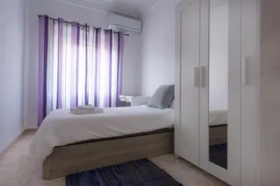 a bedroom with a bed and a window with purple curtains at City apartment in Valencia