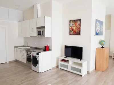 a kitchen with a washing machine and a tv at Studio Sorolla - Spacious studio near Valencia's beaches in Valencia