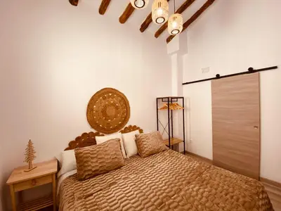 a bedroom with a bed with a large headboard at Apartamentos Casa Anselmo EL TERRAO in Losa del Obispo