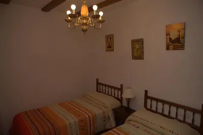 two twin beds in a bedroom with a chandelier at Casa Arminda in Benafer