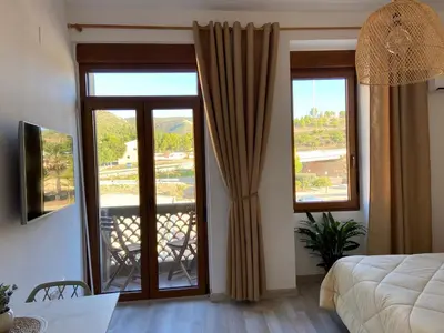 a bedroom with sliding glass doors with a balcony at Apartamento Casa Anselmo La cambra in Losa del Obispo