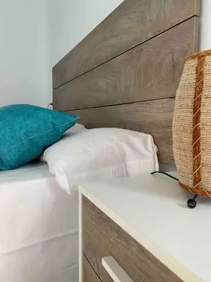 a bed with a wooden headboard and two pillows at Apartamentos LOSA RURAL in Losa del Obispo